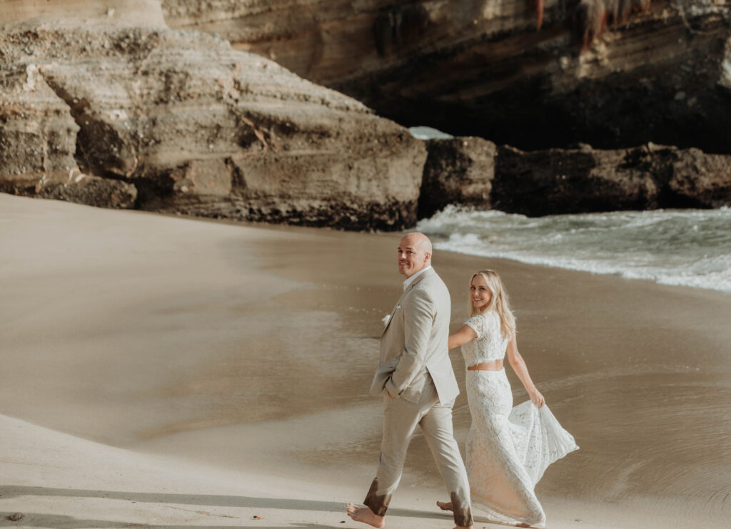 Bride and groom walk on the sand in Laguna Beach, California 