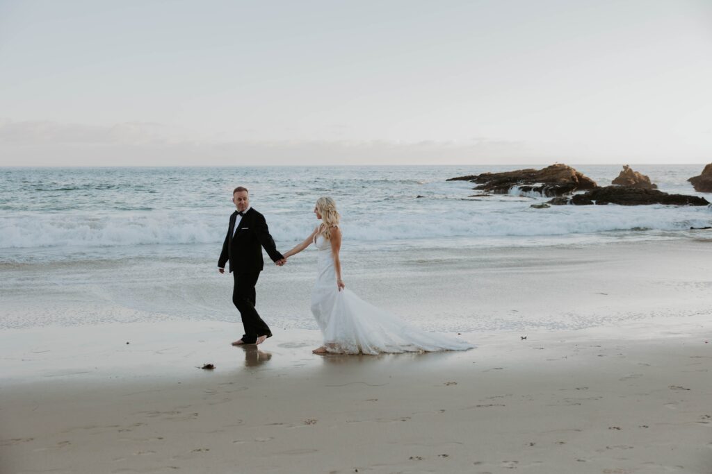 Bride and groom walk on the sand in Laguna Beach, California 